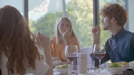 group of happy friends talking together, eating meal, drinking wine.People group enjoy modern home party dinner or lunch.Handheld video