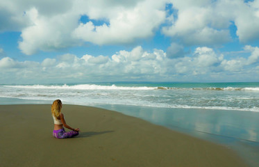 Fototapeta na wymiar young happy and attractive blond girl doing yoga and concentration exercise outdoors at beautiful beach in relax and meditation practice sitting in lotus position
