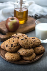 Pile of Delicious Chocolate Chip Cookies on a plate with glass of milk on wooden table