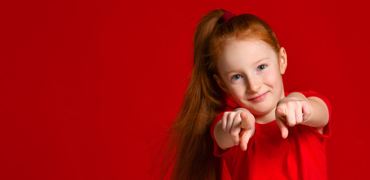 Beautiful little girl with red hair pointing to the camera with fingers