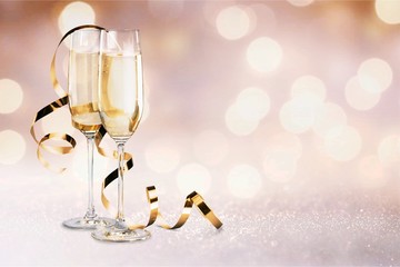 Glasses of champagne with curly ribbon on bright background