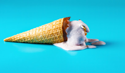 peanut ice cream cone in a melting process on blue background