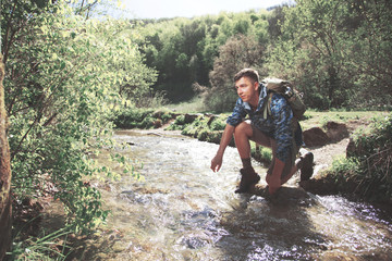 Man with backpack in a beautiful forest while hiking near a waterfall