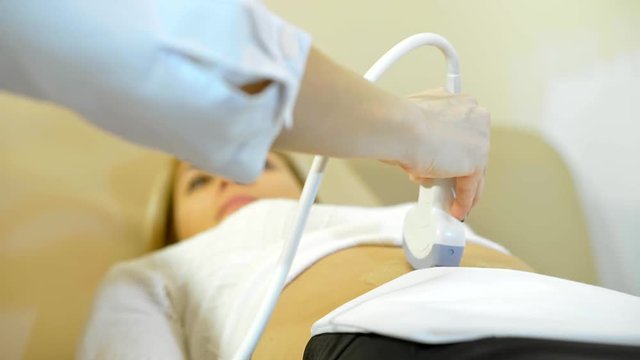 Ultrasonic in modern clinic. A close up the hand of the doctor Taking A Sonogram a stomach the woman