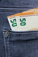money euro notes, 50 euros each peeking out of the pocket of jeans, the concept of theft, vertical
