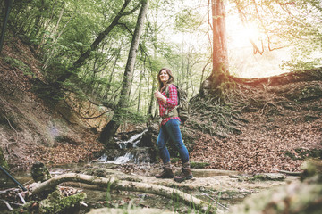 Woman with backpack in a beautiful forest while hiking near a waterfall