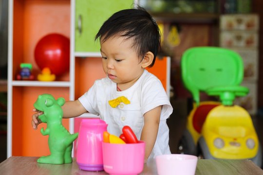 Learning and development of baby aged one year old. Happy asian child girl playing with many toys at the room.
