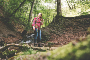 Woman with backpack in a beautiful forest while hiking near a waterfall