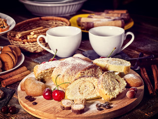 Sand nut chocolate cookies and rolled biscuit on board and cinnamon stick. Straw pastry with cup of coffee with dessert spoonon on wood kitchen table in rustic style. Limitations for diabetics.