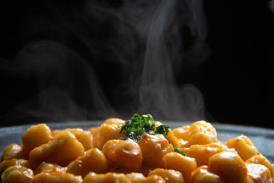 Nhoque de batata caseira com molho e salsa quentinho, saindo fuma&ccedil;a.
