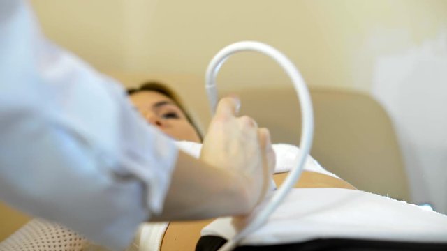 the hand of the doctor Taking A Sonogram a stomach the woman