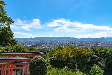 Fushimi Inari-taisha Shrine. Thousands countless vermilion Torii gates on a hill, with Kyoto city skyline view in Kyoto, Japan