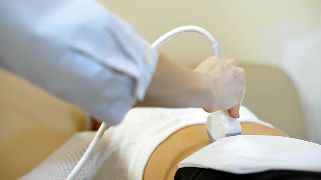 the hand of the doctor Taking A Sonogram a stomach the woman