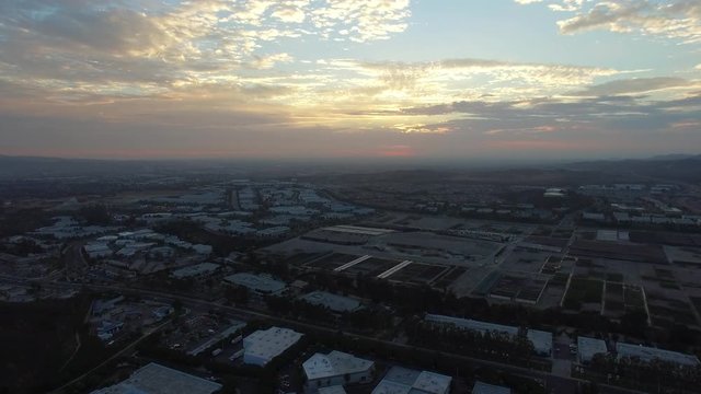 AERIAL: Golden hour skyscapes over suburban town and businesses in Southern California