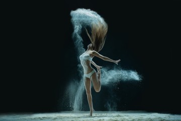 Fototapeta na wymiar Woman in lingerie dancing in sandy cloud