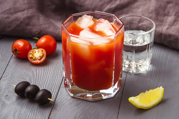 Cocktail Bloody Mary with ice in glasses on gray wooden table.