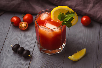 Cocktail Bloody Mary with ice in glasses on gray wooden table.