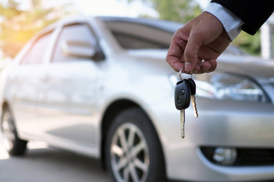 The car owner is standing the car keys to the buyer. Used car sales