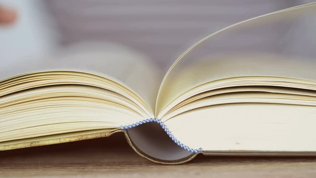 close up opened book on the table , hand hold turning the book page ,reading textbook or  learning education concept