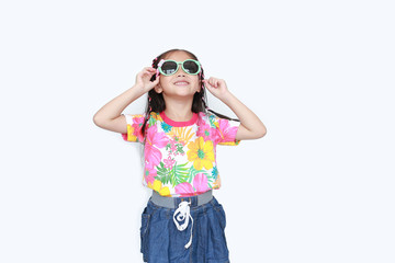 Beautiful little Asian kid girl wearing a flowers summer dress and sunglasses looking up isolated on white background. Summer and fashion concept.