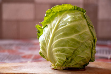 Fresh green garden cabbage on wooden cutting board in the kitchen on the table