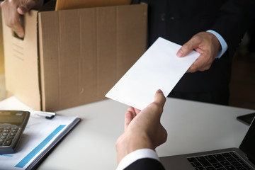 The business woman has a brown cardboard box next to her body and sends a letter of resignation to the executive. Include about resignation, job placement and vacancies.
