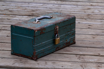 Rusty old toolbox locked up sitting on a wood