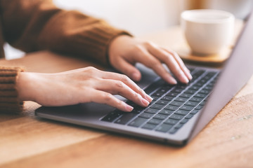 Closeup image of woman's hands using and typing on laptop computer keyboard