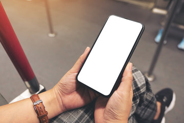 Mockup image of woman's hands holding black mobile phone with blank screen in subway