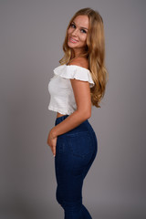 Young beautiful woman with blond hair against gray background