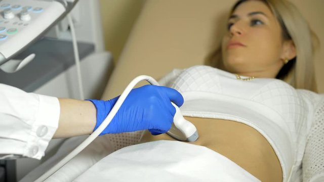 the hand of the doctor Taking A Sonogram a stomach the woman