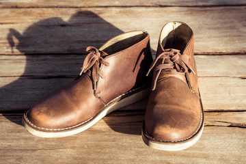 Brown stylish boots on wood background,  retro color