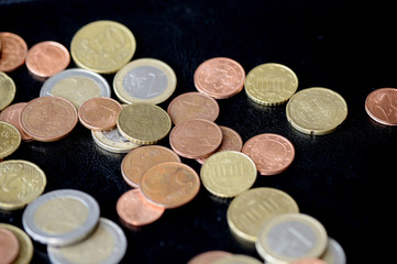 Pile of Euro coins scattered on a dark surface close up