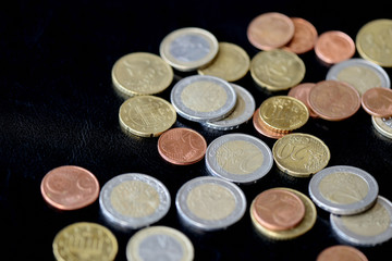 Pile of Euro coins scattered on a dark surface close up