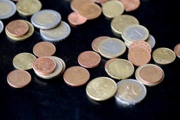 Pile of Euro coins scattered on a dark surface close up
