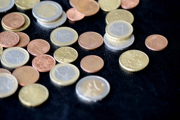 Pile of Euro coins scattered on a dark surface close up