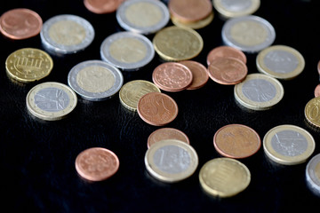 Pile of Euro coins scattered on a dark surface close up