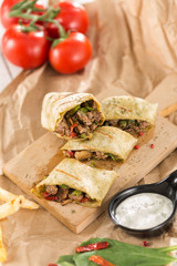Tortilla wraps sliced, meat beef burritos  and french fries with souce