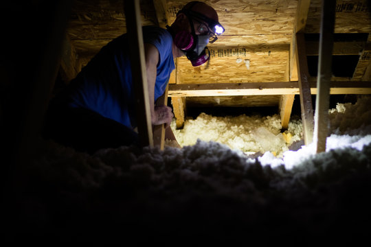Working in a dark and dusty attic with insulation