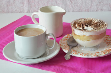 coffee with whipped cream and chocolate for breakfast. gourmet breakfast, coffee with milk, milk jug, tasty cake with whipped cream, sprinkled with chocolate or cinnamon on a raspberry background