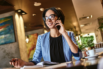 Dreams don t work unless you do. Young stylish businesswoman in a cafe talking on a cell phone