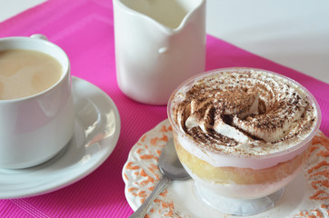 coffee with whipped cream and chocolate for breakfast. gourmet breakfast, coffee with milk, milk jug, tasty cake with whipped cream, sprinkled with chocolate or cinnamon on a raspberry background