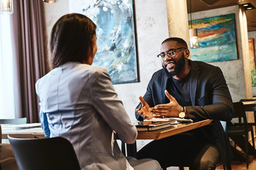 Dreams don't work unless you do. Two colleagues having lunch in company's restaurant. Focus on the man