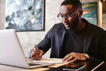 Always make a total effort, even when the odds are against you. African american businessman is working, using his laptop while resting in the cafe
