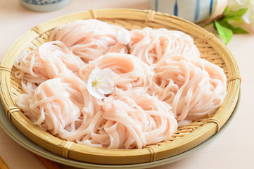 a basket of chilled sakura noodles on wooden background