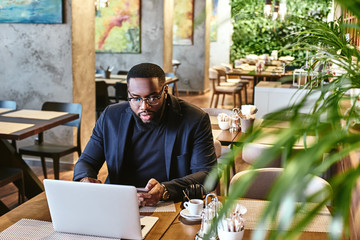 Nothing can beat hard work. African american businessman is working, using his laptop while resting in the cafe