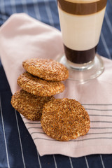 glass of latte with cookies on napkins