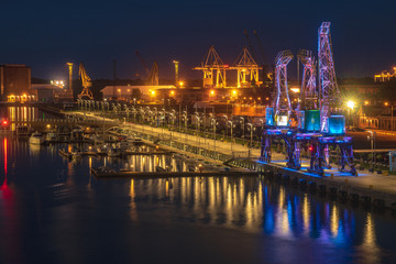 Obraz premium Oświetlone stare żurawie portowe na bulwarze w Szczecinie nocą