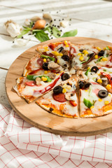 home made gourmet thin tortilla pizza on wooden plate and wood table gourmet food