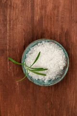 Rosemary infused sea salt, shot from above on a dark rustic wooden background with copyspace